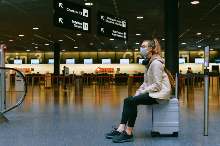 Lone masked woman waiting at airport terminal.