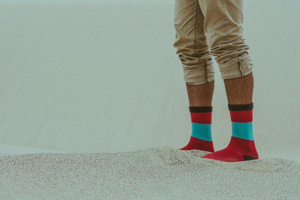 Person in socks standing in sand. 