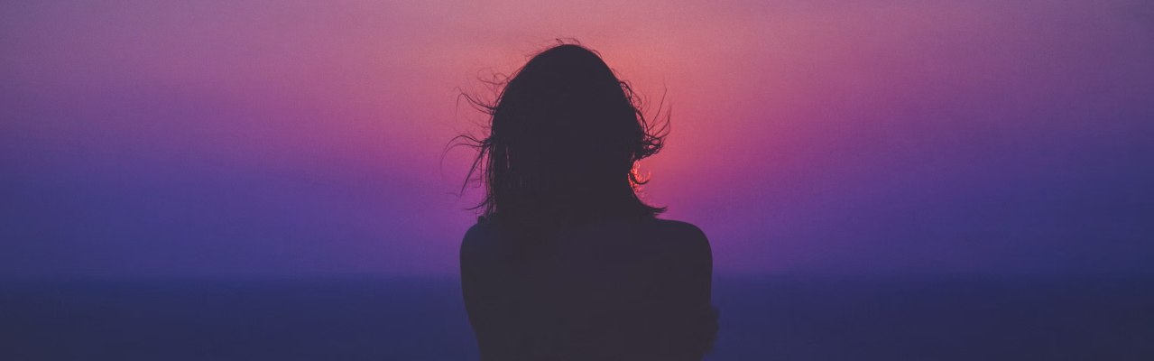 Silhouette of woman in front of a purple and pink sky.