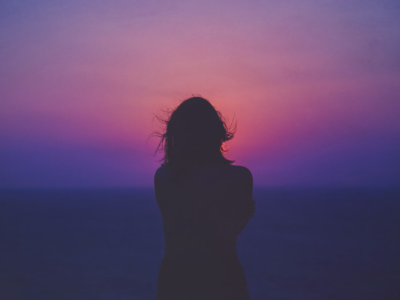 Silhouette of woman in front of a purple and pink sky.