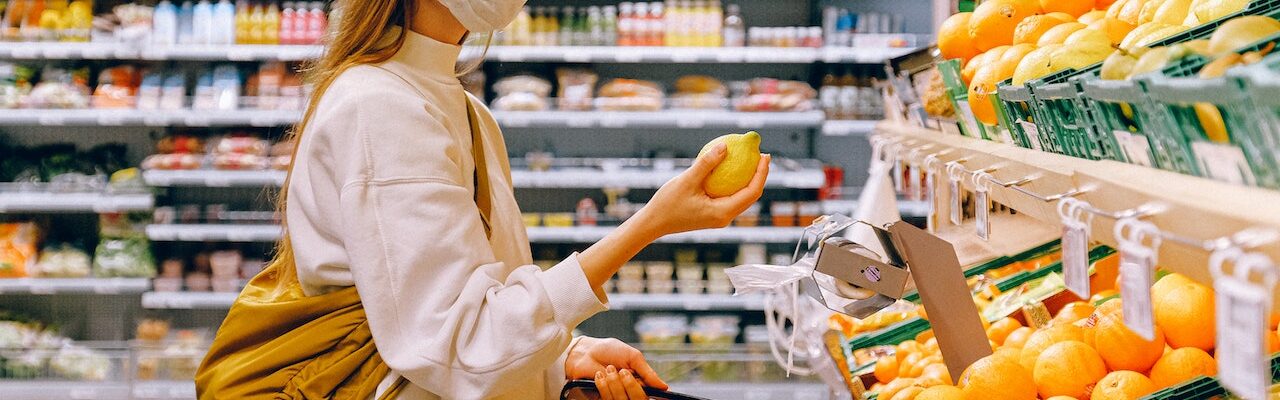 A masked woman shopping in a produce section