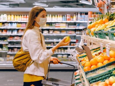 A masked woman shopping in a produce section