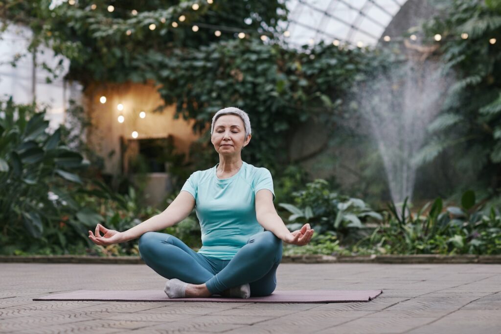 woman meditating on mat surrounded by trees