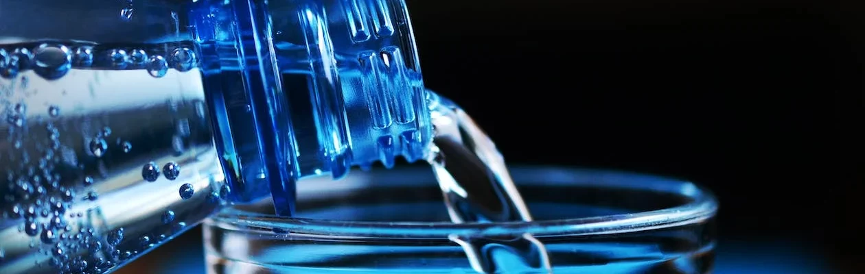 Plastic bottle pouring water into a cup.