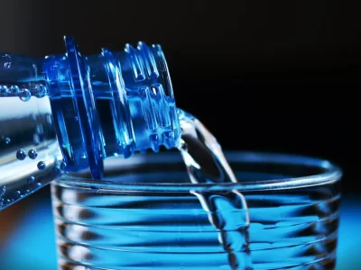 Plastic bottle pouring water into a cup.