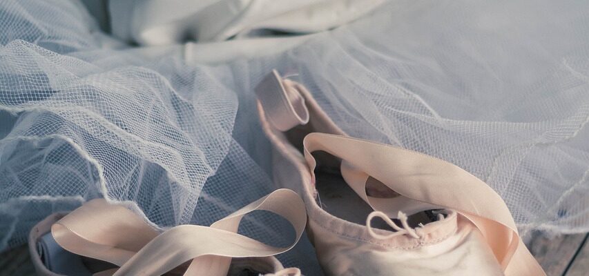 Pointe shoes and a leotard with a tutu behind the pointe shoes.