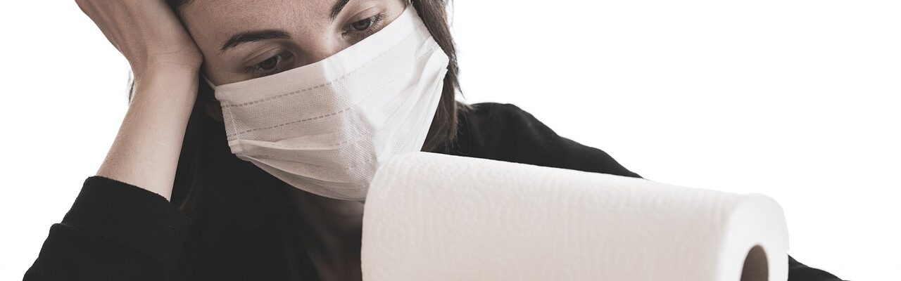 Woman with mask depressed staring at paper towels.