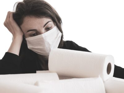 Woman with mask depressed staring at paper towels.