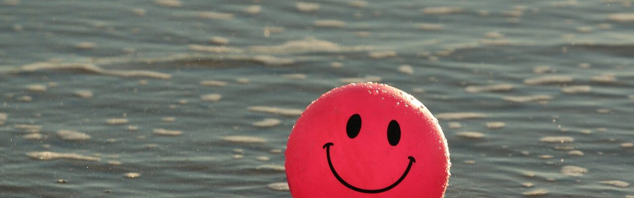 A ball with a happy face floating in water.