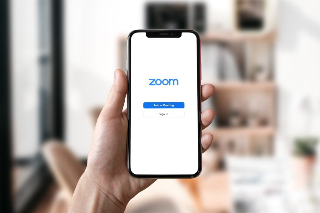 A person holding a phone with the zoom meeting app opened.