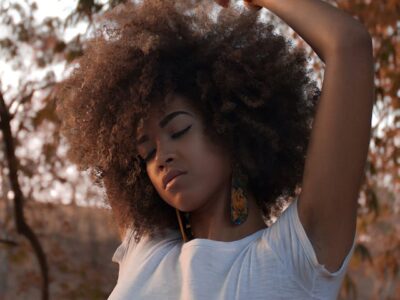 Black woman with type 4 hair posing in front of fall scenery.