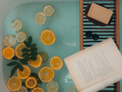 Bath with lemons in it, with soap and a book on a stool for self care.