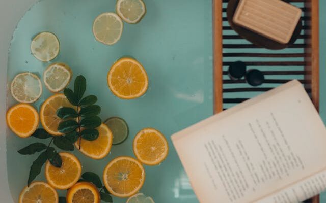 Bath with lemons in it, with soap and a book on a stool for self care.