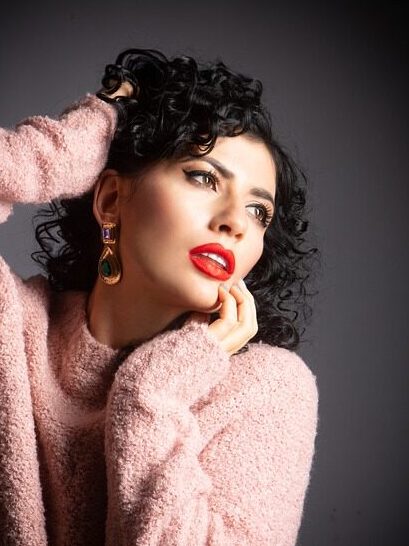 Woman with type 3 hair in pink sweater and red lipstick.