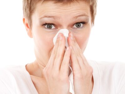 A woman blowing her nose with a tissue.