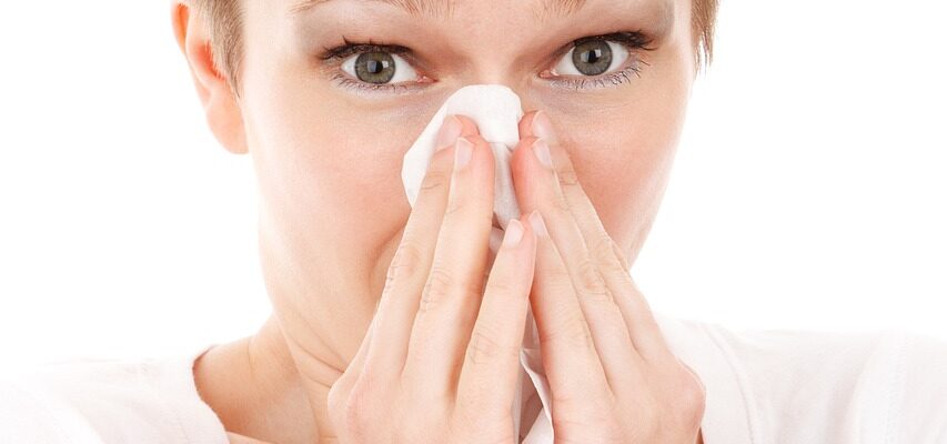 A woman blowing her nose with a tissue.