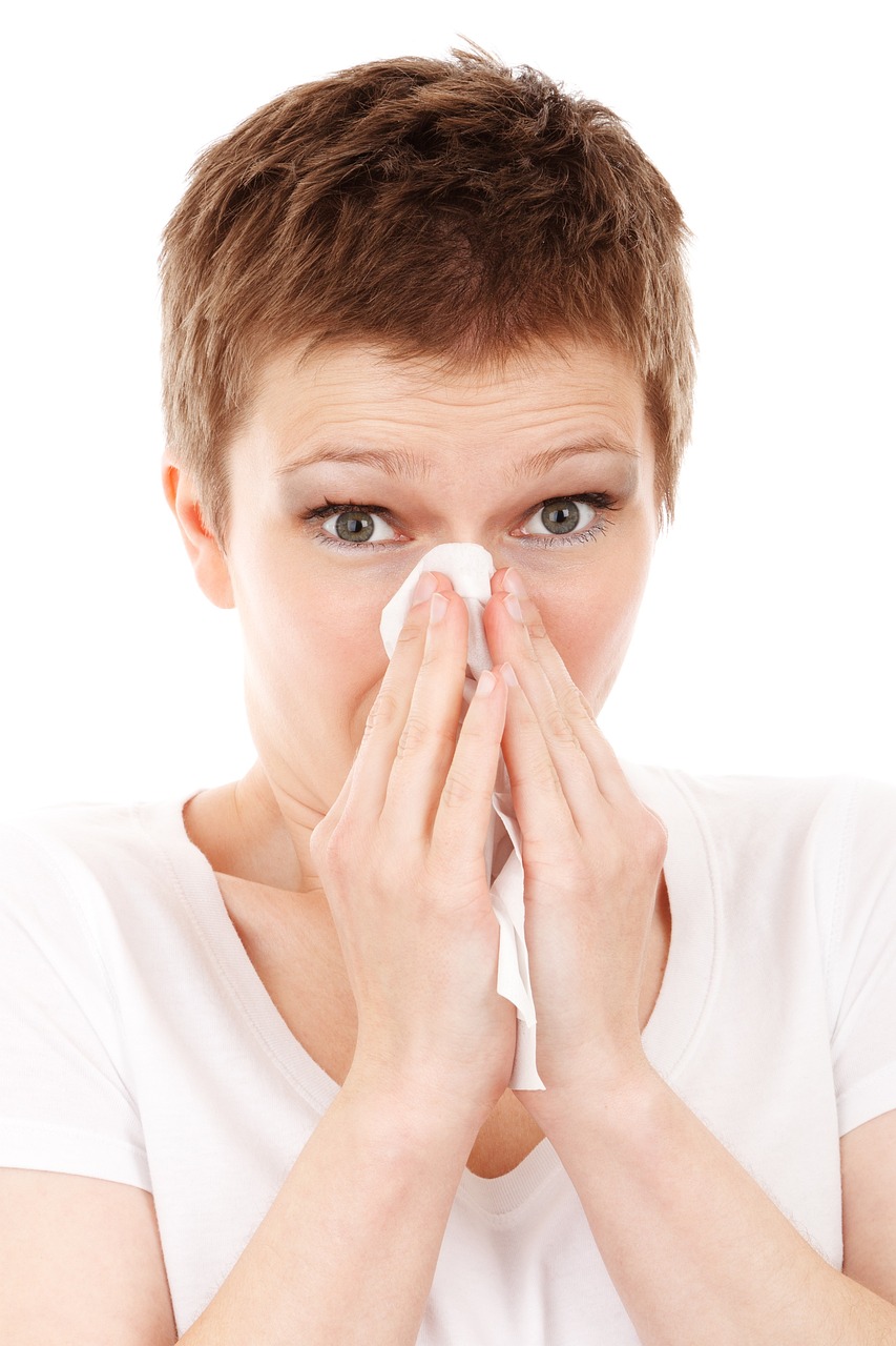 A woman blowing her nose with a tissue.